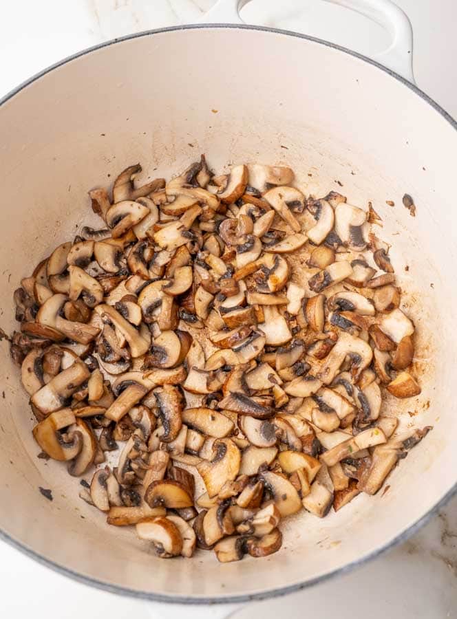 Saueteed mushrooms in a white pot.