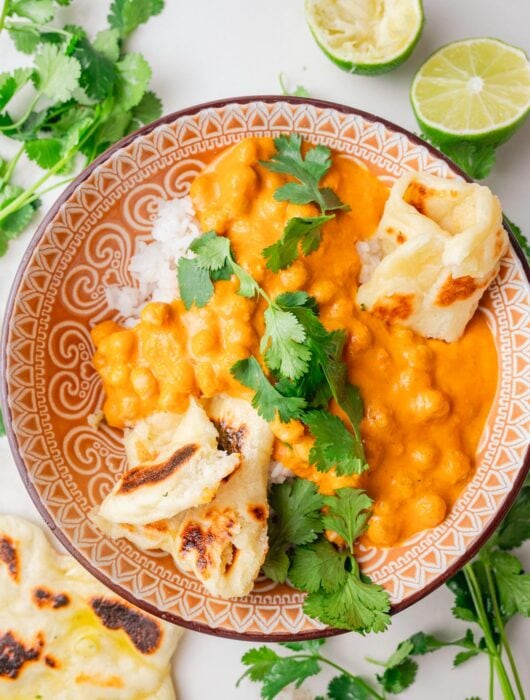 Chickpea curry with rice and pieces of Naan bread in a brown bowl.