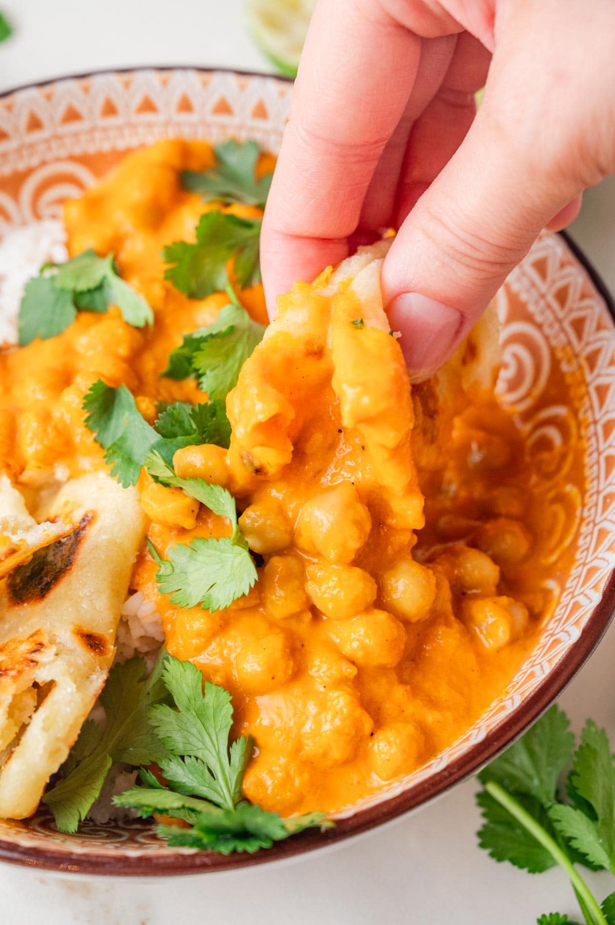 A piece of Naan bread is being dipped in chickpea curry.