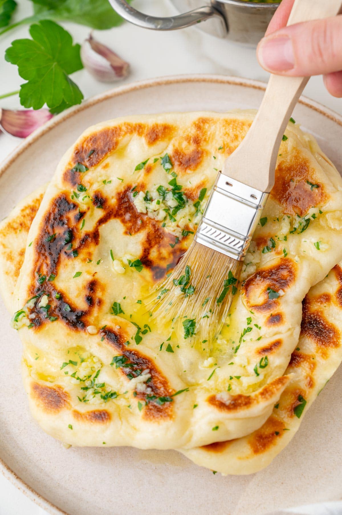 Naan bread is being brushed with garlic  butter.