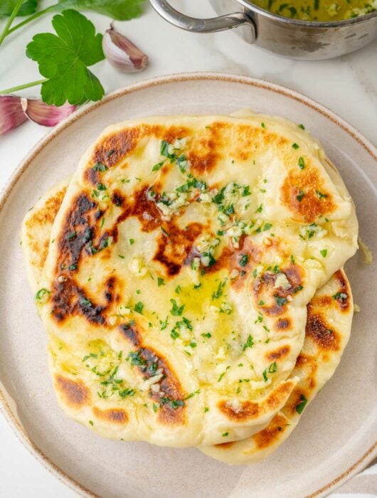 A stack of garlic Naan bread on a plate.