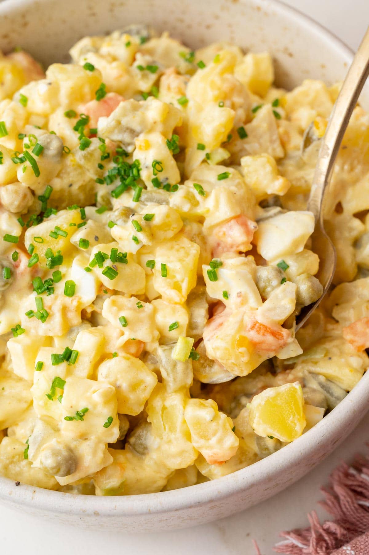 A close up photo of Polish salatka jarzynowa in a beige bowl.