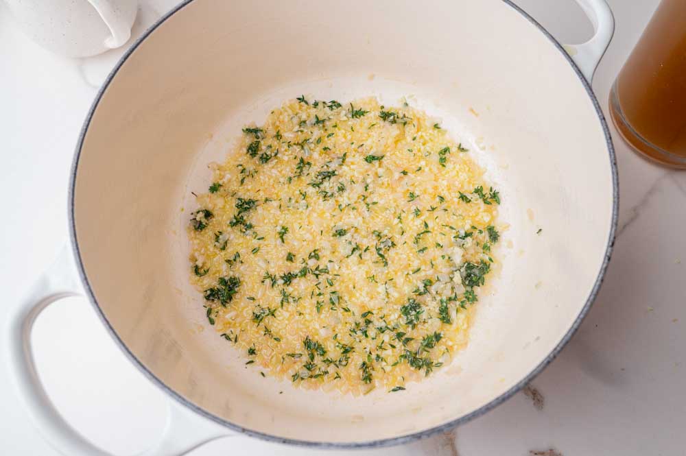 Sauteed shallots with garlic and thyme in a white pot.