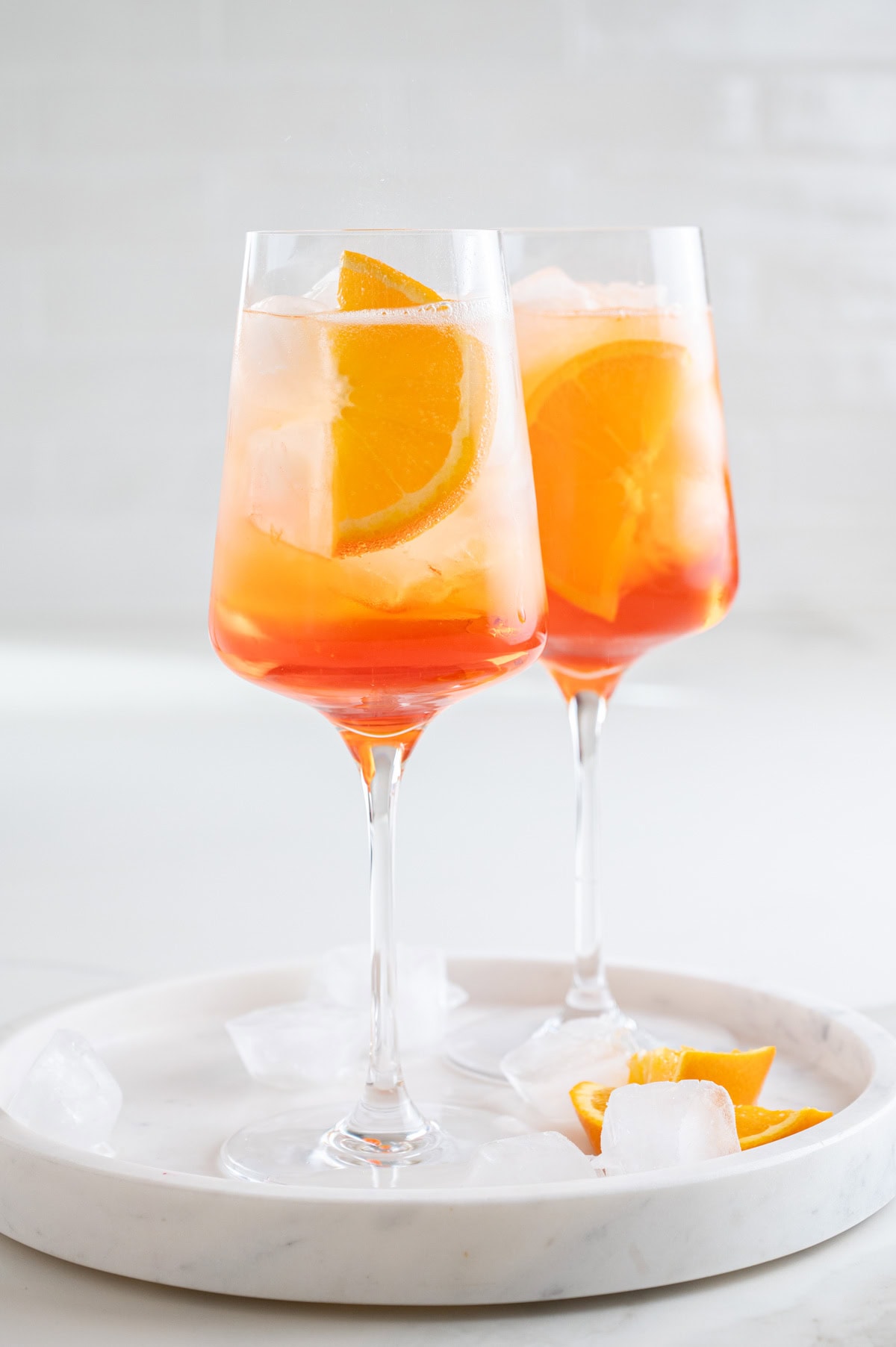 Two glasses with Aperol Spritz cocktail garnished with orange slices.