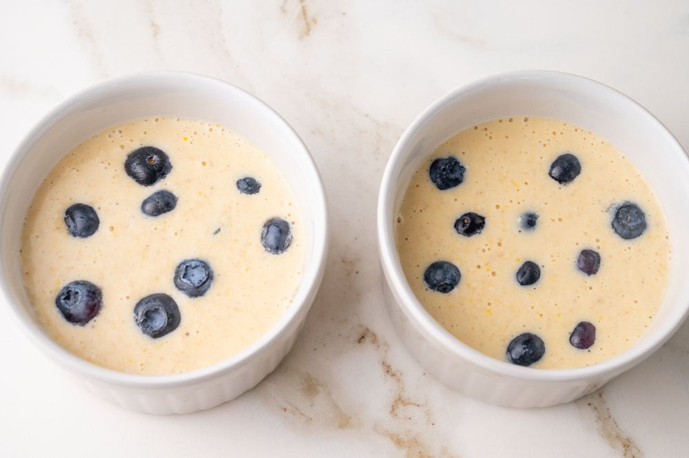 Baked oats batter with blueberries in two ramekins.