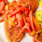 Schnitzel with bell pepper and onion sauce on a plate.