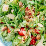A close up photo os arugula salad on a blue plate.