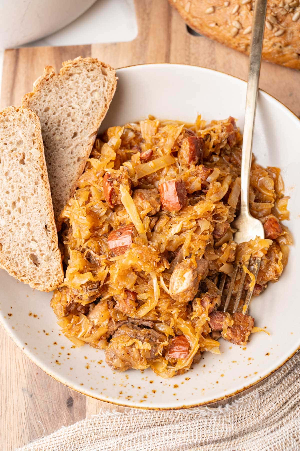 Bigos stew served with bread on a brown plate.