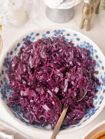 Danish red cabbage in a white bowl with blue flowers. Christmas decorations in the background.