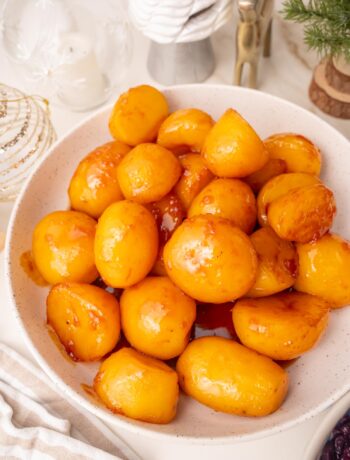 Danish caramel potatoes in a white bowl. Christmas decoration in the background.