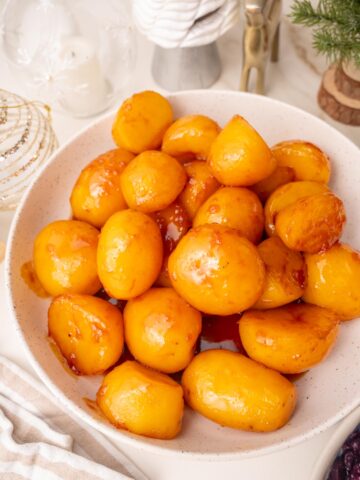 Danish caramel potatoes in a white bowl. Christmas decoration in the background.