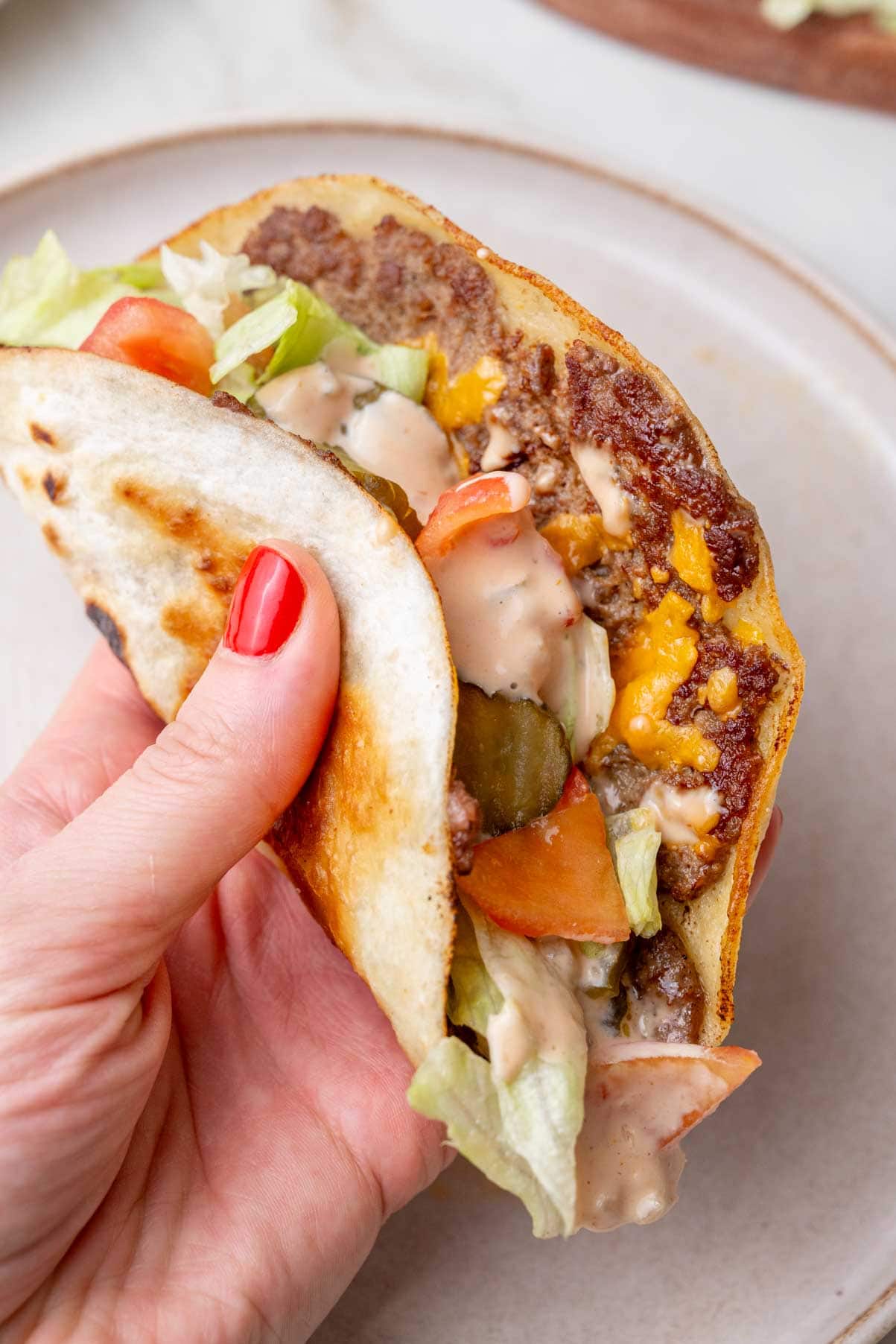 A Big Mac taco in being held in a hand - a close-up photo.